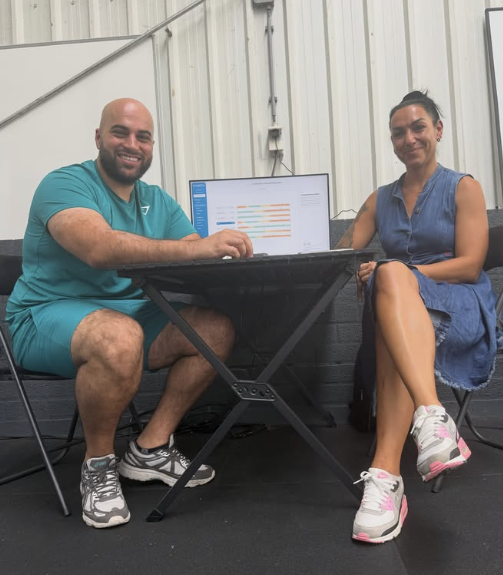 Rebar en een sporter zitten samen aan tafel in de gym