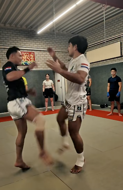 Een Muay Thai-techniek wordt voorgedaan terwijl deelnemers meekijken